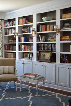 a living room filled with lots of bookshelves next to a window covered in curtains