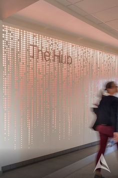 two people walking past a wall that has the word linked on it and is lit up with red lights