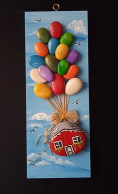 a painting of a house with balloons attached to the front of it, hanging on a wall