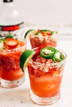 three glasses filled with different types of drinks and garnished with green peppers, limes, and salt