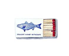 a matchbox filled with matches and two fish on top of each other next to some red matches