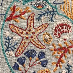 a close up of an embroidered design on a piece of cloth with seaweed, starfish and corals