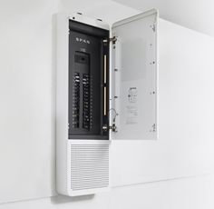 a white wall mounted computer in a corner with the door open to show it's components