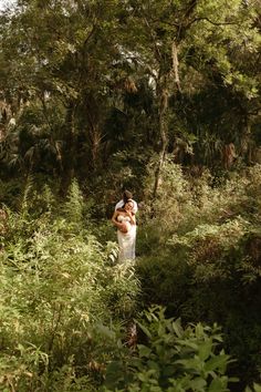 a bride and groom embracing in the woods