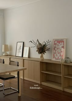 a dining room table and chairs in front of a book shelf with pictures on it