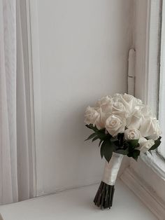 a bouquet of white roses sitting on top of a window sill