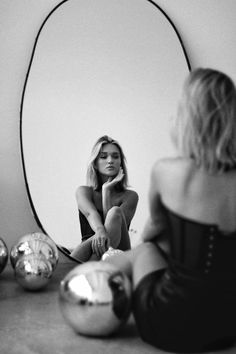 a woman sitting on the floor in front of a mirror looking at her own reflection