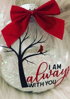 a glass ornament that says i am always with you and a red bow