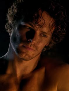 a shirtless man with curly hair and no shirt on is looking at the camera