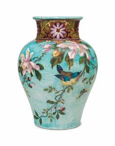 a blue vase with flowers and birds painted on the front, sitting against a white background