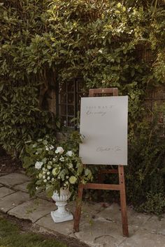 an easel with flowers in it next to a sign