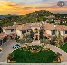 an aerial view of a mansion with cars parked in the driveway and mountains in the background