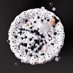 a woman laying in a bubble filled bathtub surrounded by bubbles and black and white balls