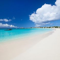 a boat is in the clear blue water on a white sandy beach near an island