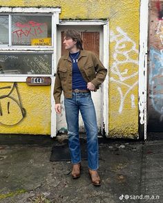 a man standing in front of a yellow building with graffiti on the wall and door