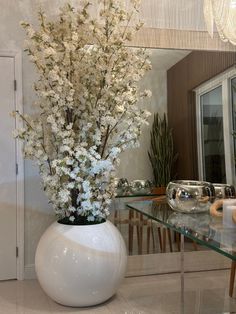 a white vase filled with flowers sitting on top of a table next to a mirror