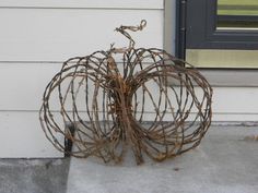 a wire pumpkin sitting on the ground next to a door