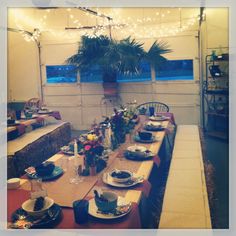 a dining room table set with plates and place settings in front of a potted plant