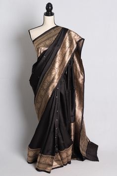 Experience the timeless elegance of our Silk Mark Certified Mashru Banarasi Silk Saree in Black and Gold, exclusively from Bengal Looms. This exquisite piece seamlessly blends tradition with modern sophistication, perfect for any special occasion. Crafted with intricate artistry, the saree reflects our commitment to quality, ensuring you receive a masterpiece that stands the test of time. Plus, enjoy free fast shipping from within the USA. Elevate your wardrobe with this stunning saree from our exclusive collection. This is a SILK MARK CERTIFIED Saree. Color : Black and Gold.  Blouse Piece : Yes ( cut and separated from the saree ). Fall Pico : Yes.  Care: Dry-Clean Only. Black Mysore Silk Saree, Formal Katan Silk Pre-draped Saree, Elegant Pre-draped Saree With Traditional Patterns For Festivals, Elegant Black Saree For Puja, Elegant Festive Pre-draped Saree With Traditional Patterns, Ceremonial Fitted Banarasi Silk Saree, Fitted Banarasi Silk Saree For Ceremonial Occasions, Elegant Paithani Silk Traditional Wear With Pallu, Black Raw Silk Saree For Wedding