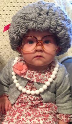 a small child wearing glasses and a gray hat with flowers on it's head