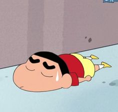 a cartoon character laying on the ground with his head down and eyes closed, in front of a wall