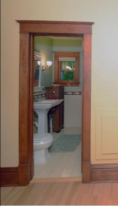 an open door leading to a bathroom with a sink and toilet in it's center