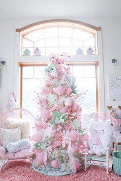 a pink christmas tree in the corner of a room with lots of stuffed animals on it