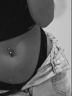 a black and white photo of a woman's stomach wearing a bra with a nose piercing