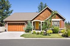 a large house with two cars parked in front of it and trees on the other side