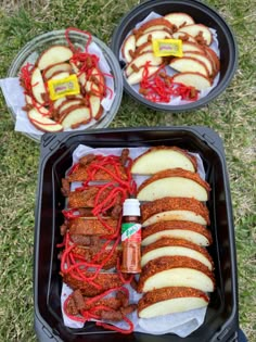 two trays filled with different types of food on top of the grass next to each other