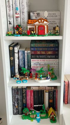 a book shelf filled with lots of books on top of white shelving unit shelves