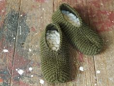 there is a pair of green knitted slippers on the wooden floor with snow flakes all over them