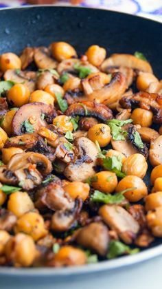 a pan filled with mushrooms and greens on top of a table