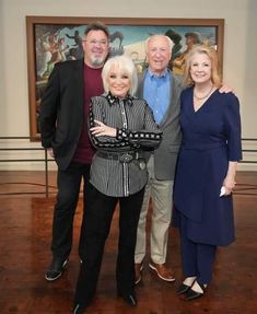 four people standing together in front of a painting