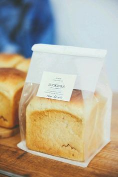 a loaf of bread sitting on top of a wooden table next to a plastic bag