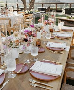 a table set with pink plates and place settings