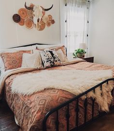 a bed with pillows and blankets on top of it next to a wall mounted deer head