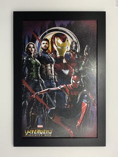 the avengers movie poster is hanging on the wall in front of a white wall with a black frame