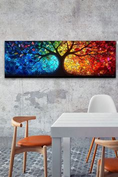 a table with chairs and a painting on the wall above it that has a colorful tree