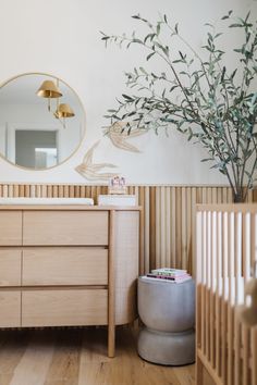 a baby's room with a dresser, mirror and potted plant in it