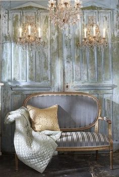 a couch sitting in front of a wooden wall with chandeliers hanging from it