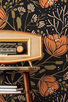 an old radio sitting on top of a wooden table next to a flower wallpaper