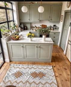 a kitchen with green cabinets and white counter tops, an area rug on the floor