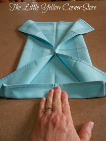 an origami piece being folded on top of a table with one hand and the other