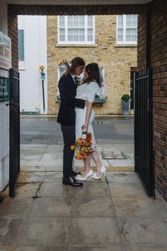 a bride and groom standing in an open doorway with their arms around each other as they kiss