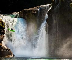 a man in a green kayak is jumping over a waterfall into the water below