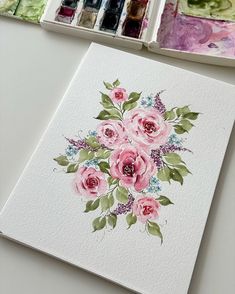 some watercolors are sitting on a table next to an art card with flowers painted on it