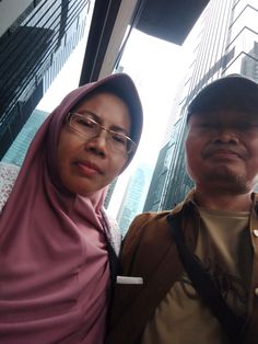 two people standing next to each other in front of tall buildings with skyscrapers behind them