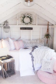 a white bed with pillows and blankets in a room next to a record player on the wall