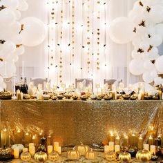 a table topped with lots of white and gold balloons